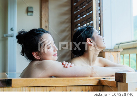 のんびり檜風呂に入る若い女性達 104528740