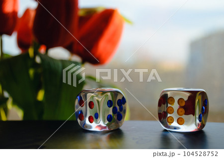 Transparent dice on the background of a window and a bouquet of red peonies 104528752