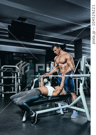 Fitness instructor exercising with his client at the gym. 104529221