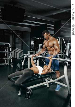 Fitness instructor exercising with his client at the gym. 104529224