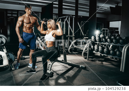 Fitness instructor exercising with his client at the gym. 104529238