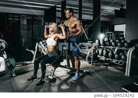 Fitness instructor exercising with his client at the gym. Fitness instructor exercising with his client at the gym. 104529242