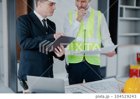 multi ethnic engineer brainstorming and measuring for cost estimating on blueprint and floor plan drawings about design architectural and engineering for houses and buildings. 104529243