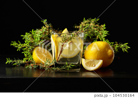 Cocktail Gin-tonic with ice, lemon, and juniper on a black background. 104530164