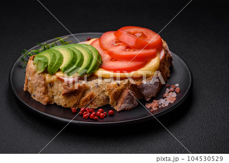 Delicious nutritious grilled toast with ham, cheese, tomatoes and avocado 104530529