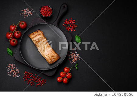 Slice of delicious baked fish with salt, spices and herbs on a ceramic plate 104530656