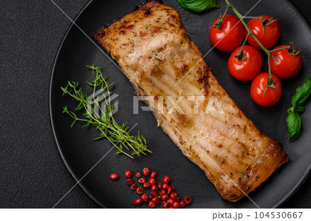 Slice of delicious baked fish with salt, spices and herbs on a ceramic plate Slice of delicious baked fish with salt, spices and herbs on a ceramic plate 104530667