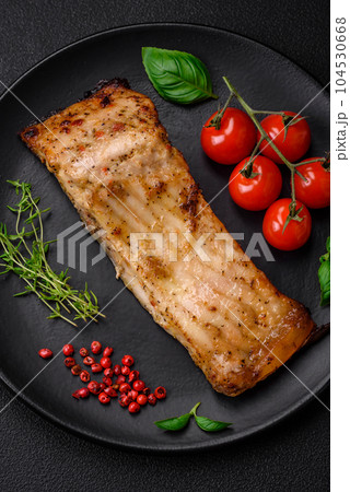 Slice of delicious baked fish with salt, spices and herbs on a ceramic plate Slice of delicious baked fish with salt, spices and herbs on a ceramic plate 104530668