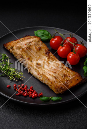 Slice of delicious baked fish with salt, spices and herbs on a ceramic plate Slice of delicious baked fish with salt, spices and herbs on a ceramic plate 104530669