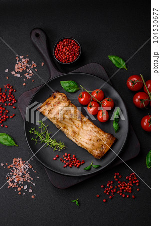 Slice of delicious baked fish with salt, spices and herbs on a ceramic plate 104530677