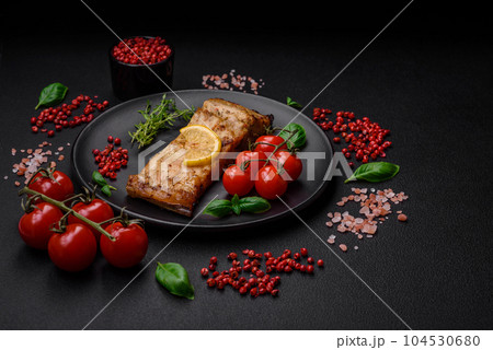 Slice of delicious baked fish with salt, spices and herbs on a ceramic plate 104530680