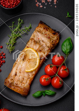Slice of delicious baked fish with salt, spices and herbs on a ceramic plate Slice of delicious baked fish with salt, spices and herbs on a ceramic plate 104530686
