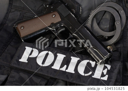 Police handgun with handcuffs on black uniform Police handgun with handcuffs on black uniform 104531825