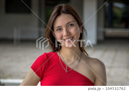 young woman brunette wearing red camisole and necklaces outside on student campus university young woman brunette wearing red camisole and necklaces outside on student campus university 104532762