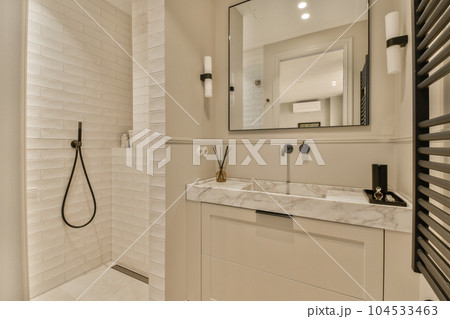 a modern bathroom with white tiles and marble counter tops on the vanity, along with a large mirror over the sink a modern bathroom with white tiles and marble counter tops on the vanity, along with a large mirror over the sink 104533463