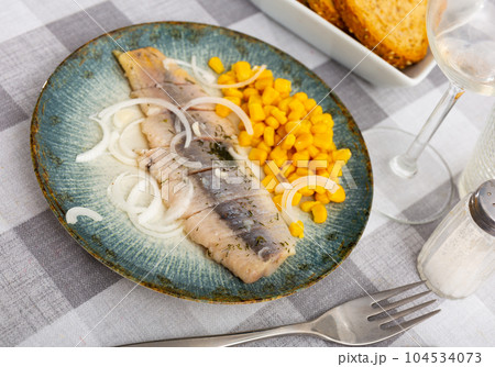 Sliced pickled herring fillet with corn and onions on plate Sliced pickled herring fillet with corn and onions on plate 104534073