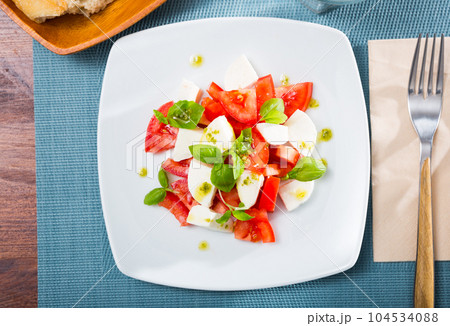 Caprese salad with fresh tomatoes, mozzarella cheese and basilic herb 104534088