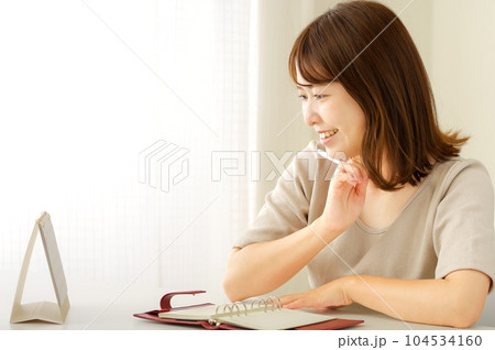 手帳を見ながら予定を考える若い女性 手帳を見ながら予定を考える若い女性 104534160