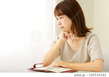 手帳を見ながら予定を考える若い女性 104534162