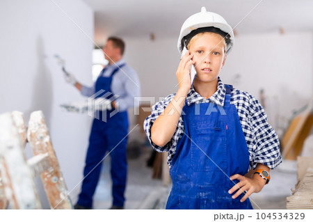 Portrait of boy in overall talking on phone Portrait of boy in overall talking on phone 104534329