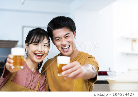 ビールで乾杯する若い夫婦 104534427