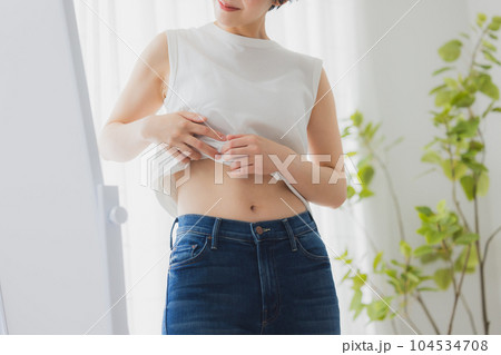 鏡でお腹をチェックする女性 104534708
