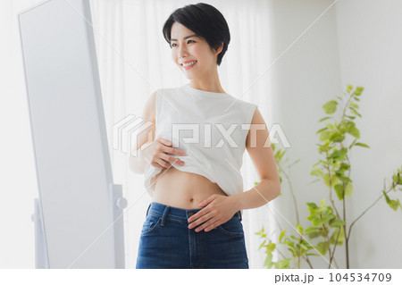 鏡でお腹をチェックする女性 104534709