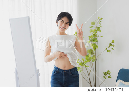 鏡でお腹をチェックする女性 鏡でお腹をチェックする女性 104534714