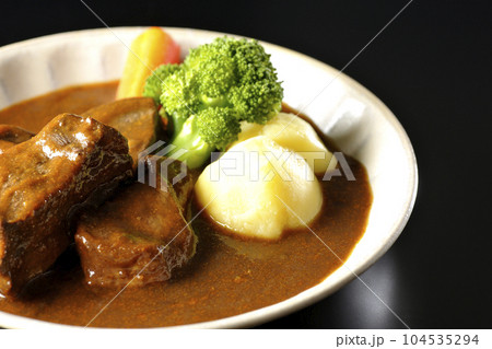 ブロッコリー、人参、ジャガイモが付け合わせてある厚切り牛タンのビーフシチューを黒背景で撮影 ブロッコリー、人参、ジャガイモが付け合わせてある厚切り牛タンのビーフシチューを黒背景で撮影 104535294