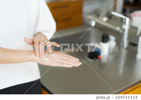 ハンドクリームを塗る女性の手元 104535314