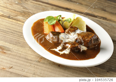 クレソン、人参、ジャガイモの付け合わせとクリームがかかっている厚切り牛タンのビーフシチュー 104535726