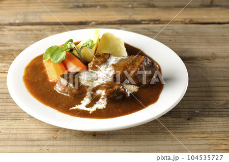 クレソン、人参、ジャガイモの付け合わせとクリームがかかっている厚切り牛タンのビーフシチュー 104535727