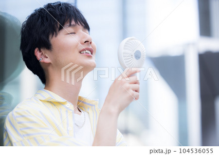 携帯扇風機で涼んでいる若い男性 携帯扇風機で涼んでいる若い男性 104536055