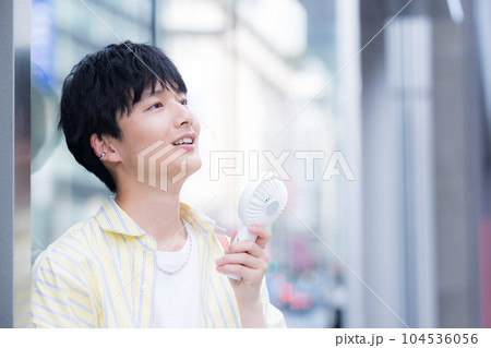 携帯扇風機で涼んでいる若い男性 携帯扇風機で涼んでいる若い男性 104536056