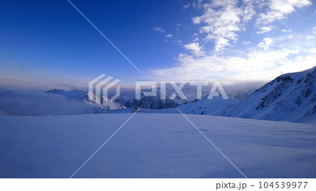 Ocean of clouds in snowy mountains at dawn Ocean of clouds in snowy mountains at dawn 104539977