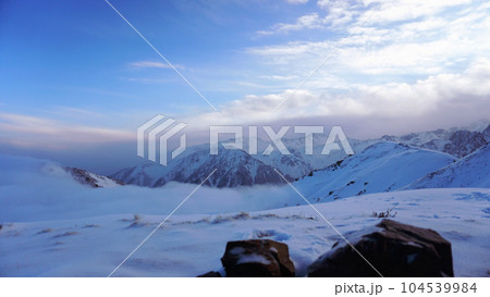 Ocean of clouds in snowy mountains at dawn Ocean of clouds in snowy mountains at dawn 104539984