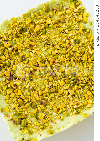 Scoring pistachio fudge using a wheel dough cutter for cutting into small square pieces. Scoring pistachio fudge using a wheel dough cutter for cutting into small square pieces. 104540203