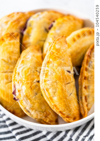 Freshly baked sweet empanadas with blueberries on the kitchen counter. 104540259