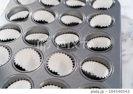 Scooping cupcake batter with a dough scoop into cupcake foil