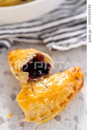 Freshly baked sweet empanadas with blueberries on the kitchen counter. 104540346