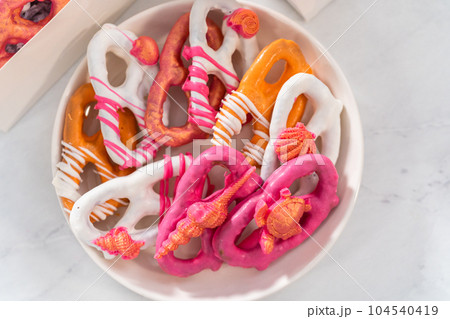 Packaging gourmet chocolate-covered pretzel twists into a white paper gift box filled with paper shreds. Packaging gourmet chocolate-covered pretzel twists into a white paper gift box filled with paper shreds. 104540419