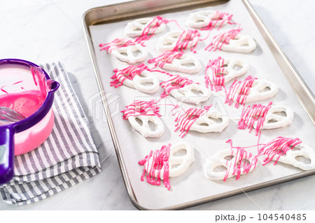 Drizzling melted chocolate over chocolate-dipped pretzels twists. 104540485