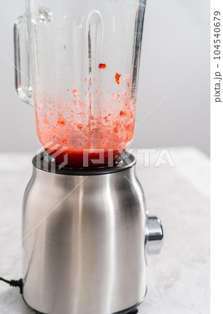 Blending fresh strawberries in a kitchen blender to prepare the strawberry buttercream frosting. Blending fresh strawberries in a kitchen blender to prepare the strawberry buttercream frosting. 104540679