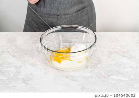 Mixing ingredients in a glass mixing bowl to bake s'mores cupcakes. 104540682