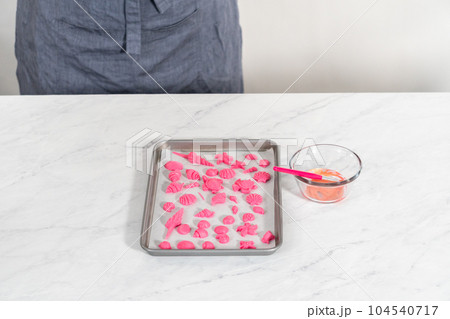 Painting sea-shaped chocolates with glittery luster to decorate chocolate-dipped pretzels twists. 104540717