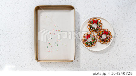 Flat lay. Removing a chocolate pretzel Christmas wreath from the parchment paper. 104540729