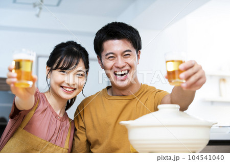 ビールで乾杯する若い夫婦 104541040