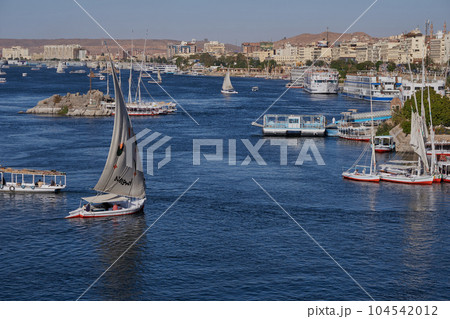 Nile river in Aswan, Egypt afternoon shot showing feluccas and boats in the river with elephantine Island (UNESCO World Heritage site) 104542012
