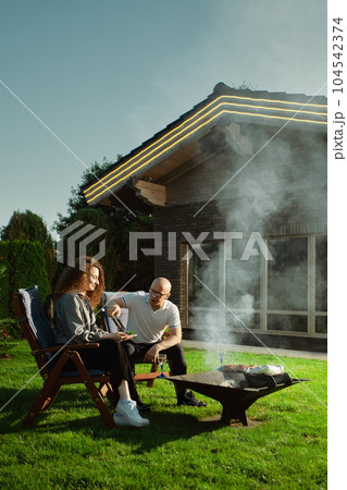 Man put grilled meat on woman's plate Man put grilled meat on woman's plate 104542374