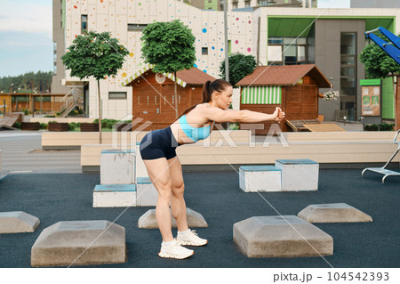A muscular fitness woman bends forward in the sports area of a residential area 104542393